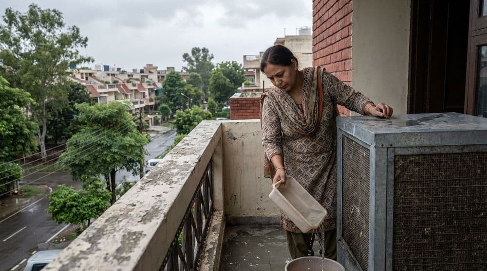 A person preventing dengue by cleaning a water tray from a desert cooler in a North Indian home. A person preventing dengue by cleaning a water tray from a desert cooler in a North Indian home.